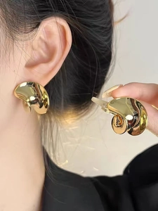 Primer plano de pendientes bañados en oro con un diseño moderno de superficie ondulada