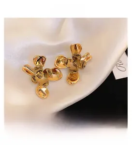 Macro view of gold plated flower studs showing smooth metallic texture on white satin