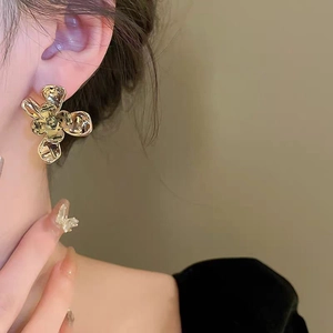 Elegant gold-plated floral earrings with textured liquid metal petals on a model's ear