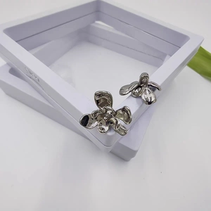 Detailed view of silver flower earrings with multilayered petals on white jewelry stand