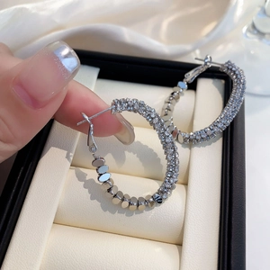 Boucles d'oreilles créoles argentées avec micro-pavage de cristaux dans un écrin de luxe