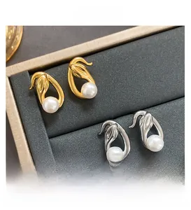 Detailed view of elegant snake-style gold and silver pearl earrings in a luxury display case