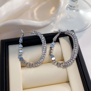 Vue détaillée des boucles d'oreilles créoles argentées serties de zircons et disques polis