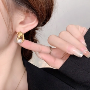 Detailed view of gold plated snake-style earrings with round white pearl on ear lobe