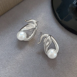 Elegant silver snake shape stud earrings with white round pearls on grey velvet