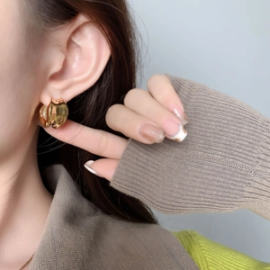 Boucles d'oreilles créoles géométriques dorées minimalistes sur un modèle