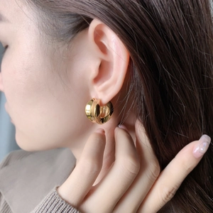 Gros plan de boucles d'oreilles créoles dorées épaisses portées par un mannequin