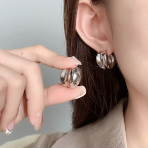Gros plan de boucles d'oreilles créoles géométriques argentées au fini miroir poli