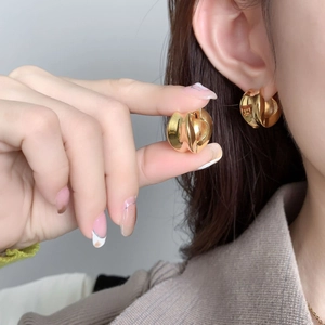 Vue macro de boucles d'oreilles créoles dorées épaisses avec finition miroir et design épuré