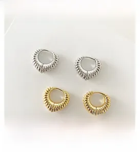 Detail of heart-shaped earrings with pleated texture in gold and silver finish