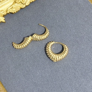 Textured gold twist hoop earrings with horn-shaped ribbed design on a gray background