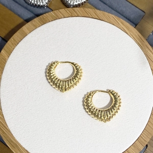 Detailed view of gold textured heart hoop earrings with radial ribbed patterns and clasp
