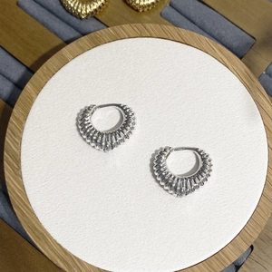Detail of silver croissant hoop earrings with vertical ribbed texture on white fabric