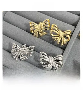 Detailed view of 3D bow stud earrings in gold and silver finish on velvet display