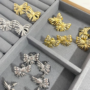 Chic 3D hollow bow earrings in polished gold and silver finish on a jewelry tray