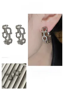 Close-up of C-shaped chain hoop earrings in silver finish with pavé crystal accents