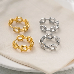 Detail of gold and silver Gancini style hoop earrings with micro-inlaid zircon and smooth finish