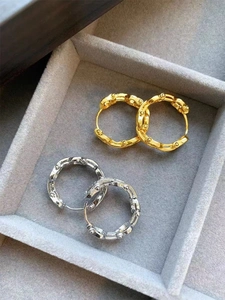Detailed view of bamboo-textured gold and silver hoop earrings on a velvet tray