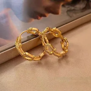 Macro shot of gold-plated chain link earrings with white zircon on silk fabric