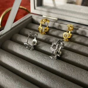 Detail of gold and silver chain link hoop earrings with micro-pave crystals in a velvet box