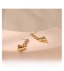 Detail view of heart-shaped gold-plated earrings with pavé crystals on a display