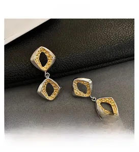 Detail of dual-tone geometric rhombus earrings with hammered gold and silver texture