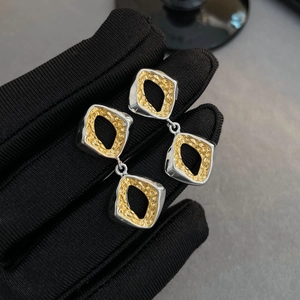 Detail view of two-tone geometric earrings with silver frames and hammered gold texture