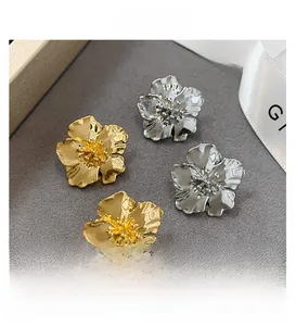 Détails macro des boucles d'oreilles fleurs dorées et argentées à texture pétale