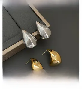 Macro detail of polished gold and silver waterdrop earrings on jewelry display