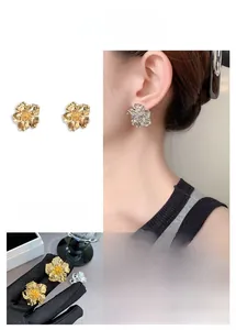 Détail des boucles d'oreilles fleur en métal avec textures plissées et finitions dorées