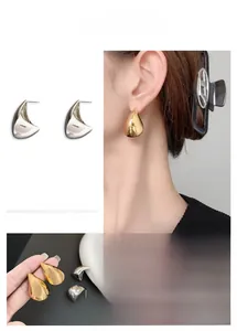 Macro shot of minimalist polished hollow teardrop earrings in gold and silver finish