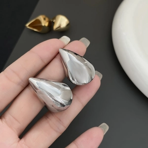Macro shot of silver teardrop earrings featuring high-gloss mirror polished finish