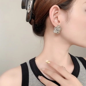 Gros plan d'une boucle d'oreille fleur en argent texturé portée par un mannequin