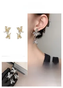 Detailed close-up showing gold and silver butterfly earrings with artistic irregular design
