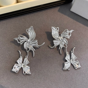 Detail view of silver fluid butterfly earrings with smooth metallic mirror finish