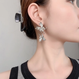 Elegant silver butterfly statement earring worn by model on a clean grey background