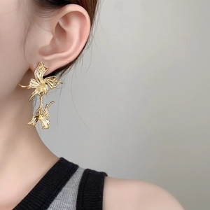 Macro detail of layered gold floral statement earrings with textured metallic petals