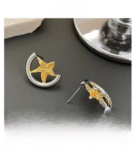 Detailed shot of two-tone star stud earrings with silver arc and gold textured star