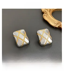 Detailed close-up of rectangular quilted earrings with gold rope patterns on silver base