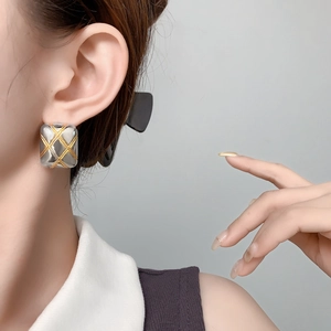 Two-tone quilted square stud earrings in gold and silver finish on a model