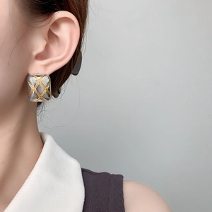 Close-up of geometric quilted texture earrings in mixed gold and silver tones on model