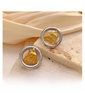 Détail de boucles d'oreilles bicolores avec anneau argenté et triangle doré texturé