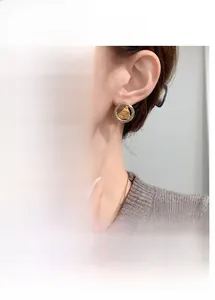 Détail de créoles argentées avec incrustation dorée texturée irrégulière et design bicolore