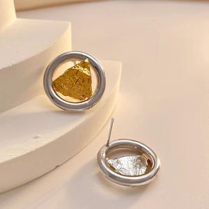Vue détaillée de boucles d'oreilles bicolores sur un support beige minimaliste