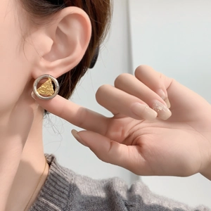 Boucles d'oreilles bicolores avec cercle argenté et triangle doré texturé portées sur l'oreille