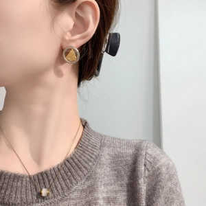 Gros plan de boucles d'oreilles rondes argentées avec détails triangulaires en feuille d'or