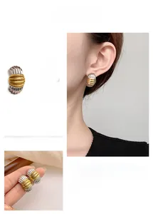 Detail of two-tone gold and silver striped metal earrings with geometric texture