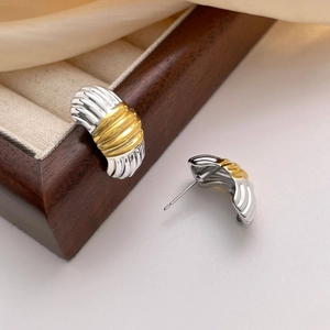 Macro detail of two-tone gold and silver corrugated stud earrings with ripple texture