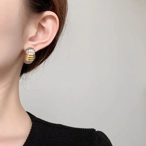 Close-up of a two-tone gold and silver striped croissant earring worn by a model