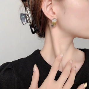 Close-up of gold and silver striped hoop earrings on model highlighting metallic texture